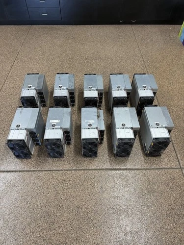 A Bitmain Antminer S21 XP photographed from the front, showing its intake fan and the power supply mounted on top of the chassis.