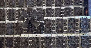Stacked Antminer S19s with a floor fan pushing air across them.