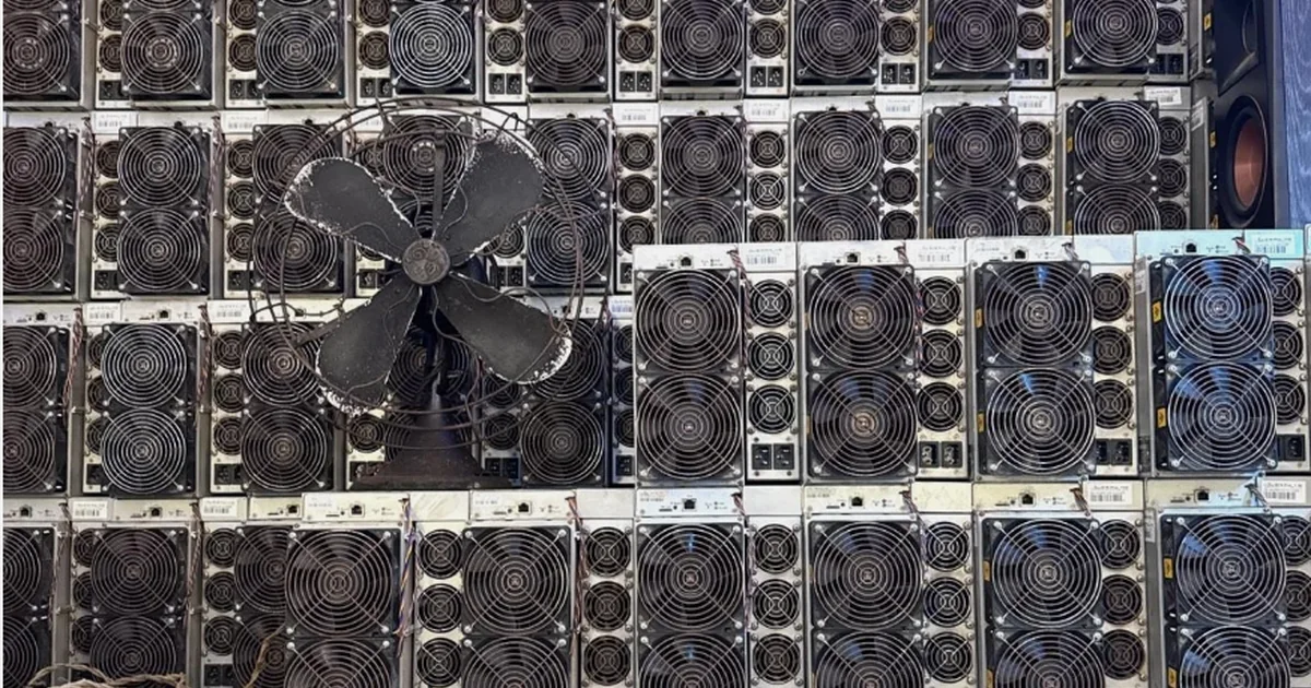 Stacked Antminer S19s with a floor fan pushing air across them.