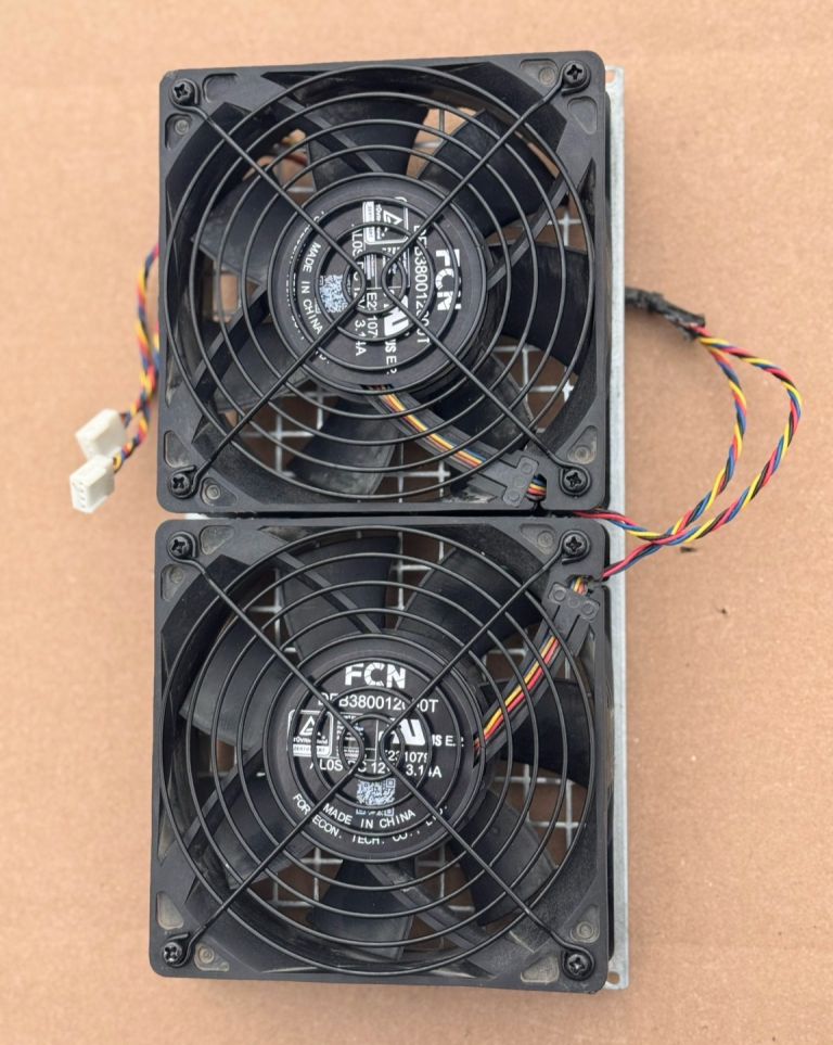 Two replacement Antminer cooling fans with black plastic frames and wire tails, photographed side by side on a wooden surface.