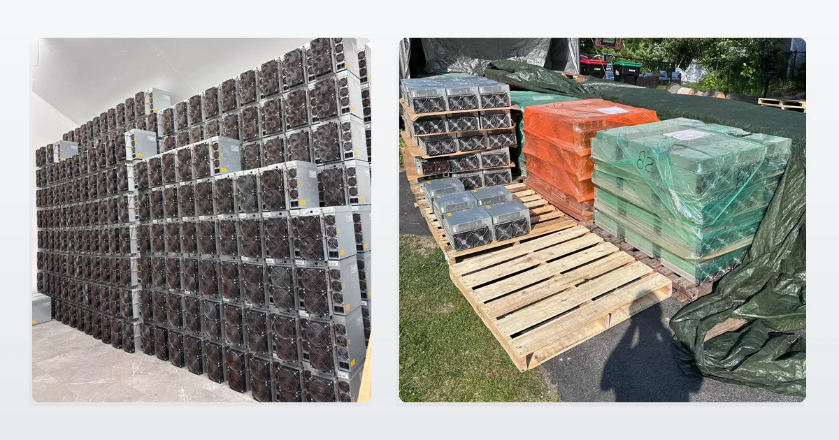 Used Bitmain Antminer S19 miners stacked several rows high against a warehouse wall, beside more S19 units shrink-wrapped in orange and green on wooden pallets outdoors.