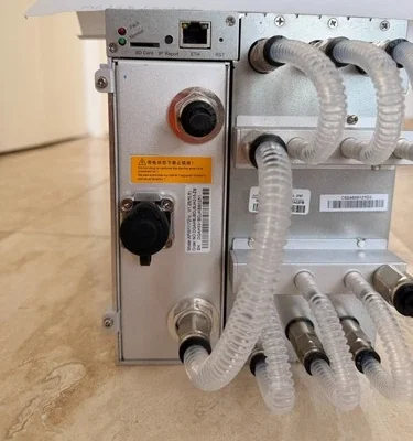 The rear panel of the Antminer S19 XP Hyd: quick-release coolant fittings, clear hoses and the control board's ports and SD slot.